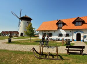 Exterier budovy Bukovanskeho mlyna s pohledem na vetrny mlyn