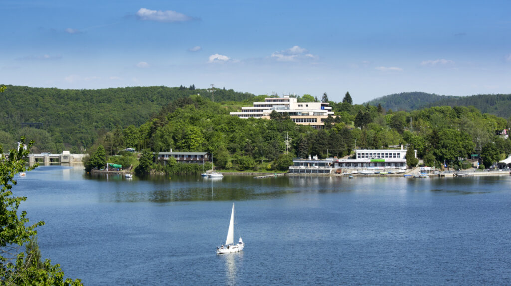 Pohled na Orea resort Santon pres prehradu, na ktere pluje lod
