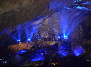 Hudebni soubor v prstorach modre osvetlene jeskyne