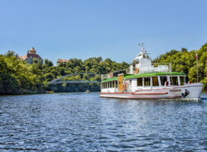 A boat sailing along the Brno dam, in the background you can see the bridge and the Veveri castle