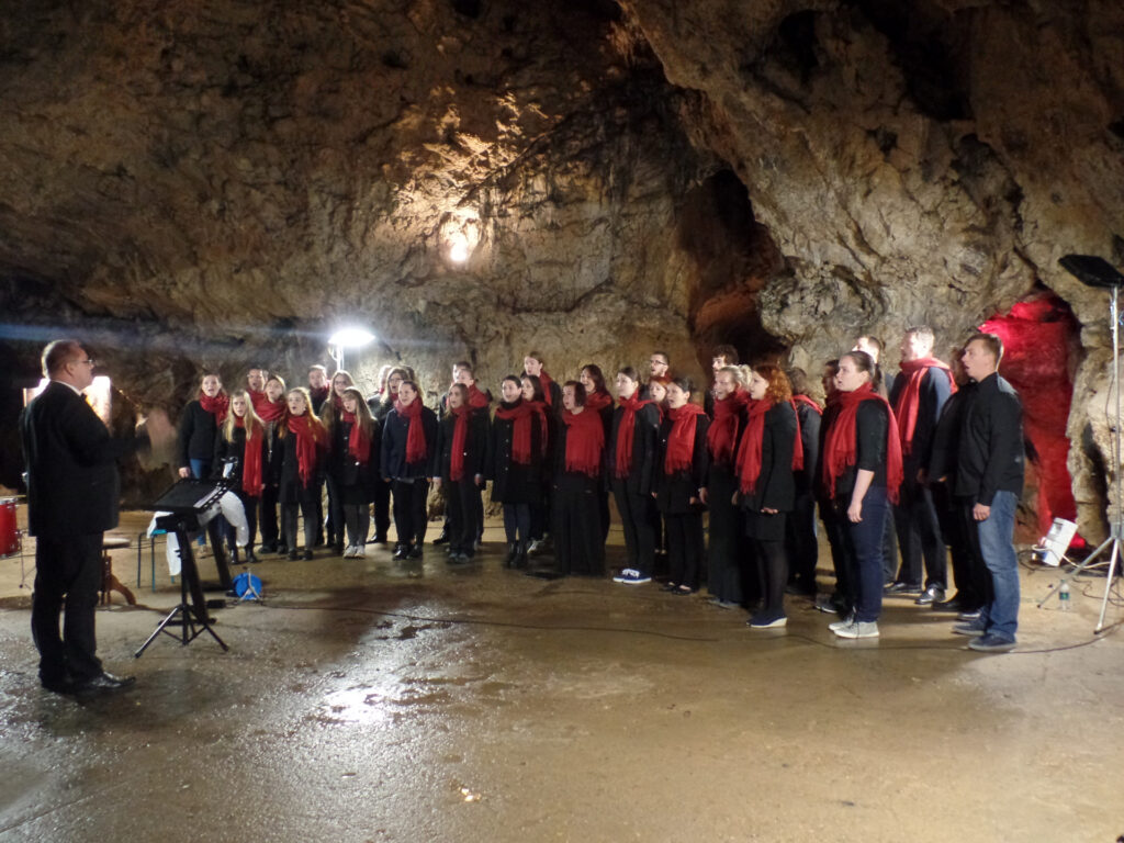 A choir with red scarves in the cave