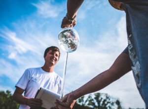 A wine thief with white wine under a blue sky