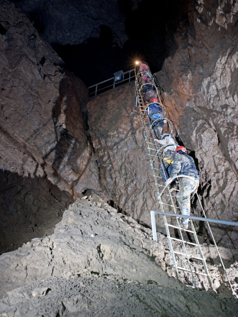 Group of people in a cave climbing a ladder