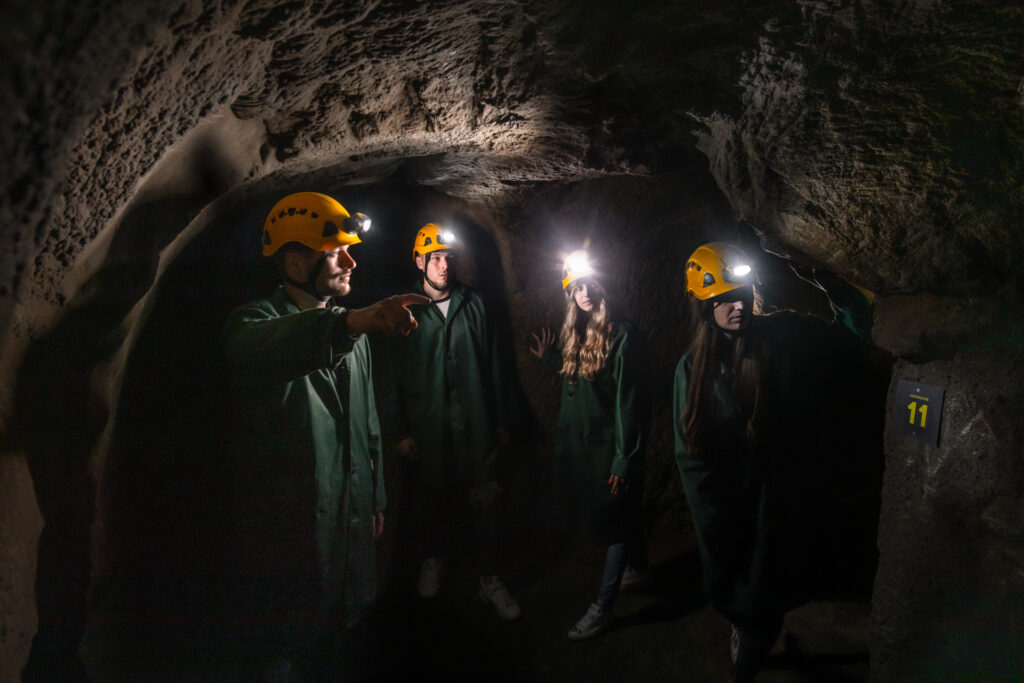 A group of people in green overalls with yellow helmets in the Znojmo underground