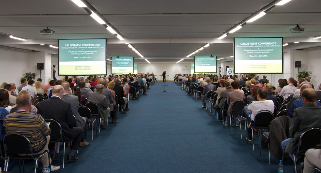 Conference at the Brno Exhibition Center with a theater-style arrangement with lots of people and projection screens