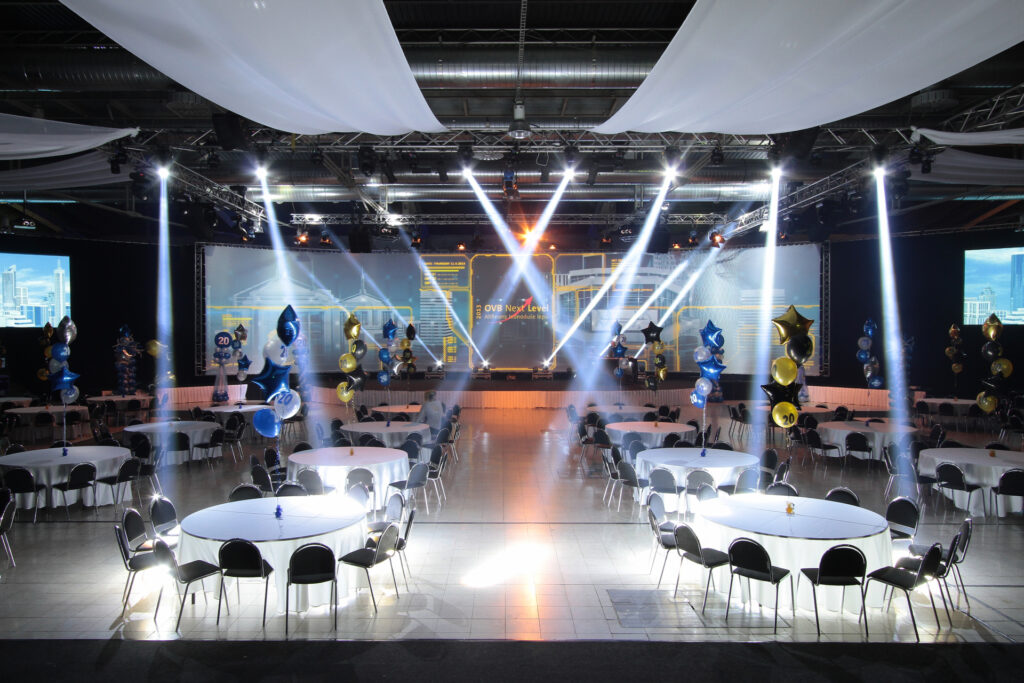 A conference room with a banquet-style arrangement without people, illuminated by spotlights