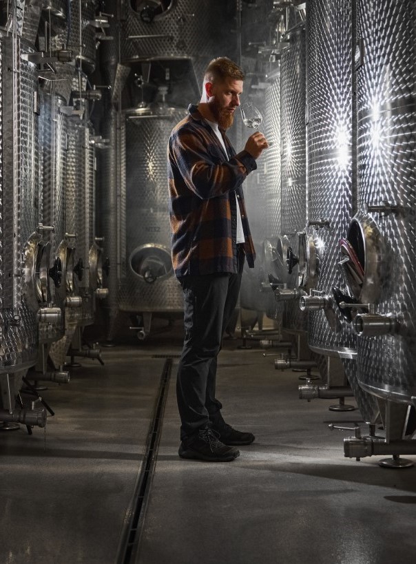 Wine maker in the middle of the room full of wine tanks