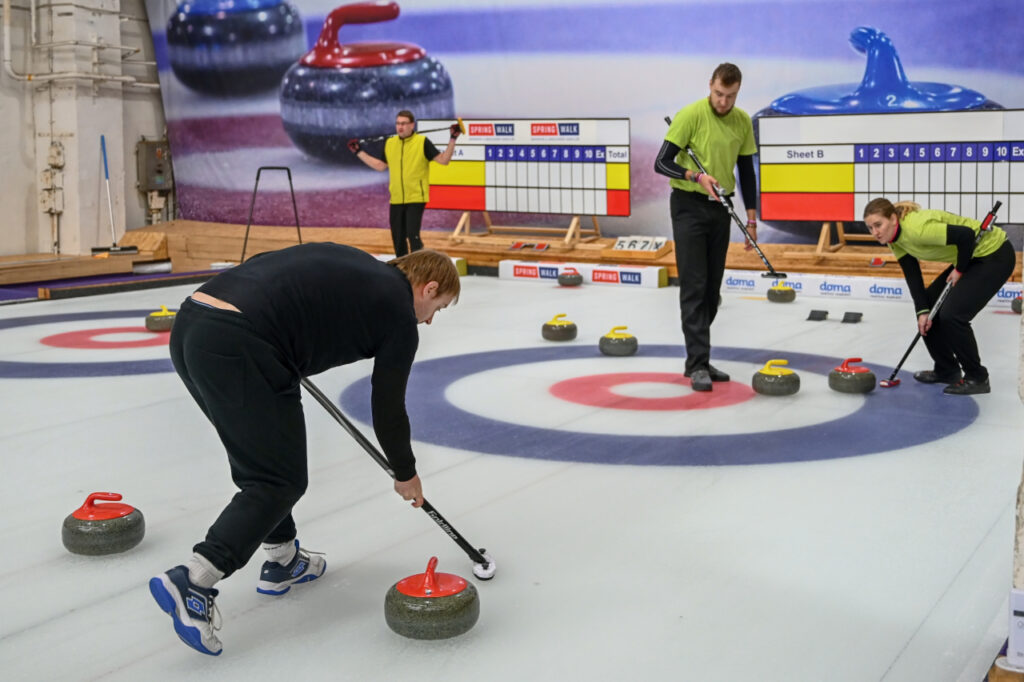 Two teams of players at the end of the curling rink